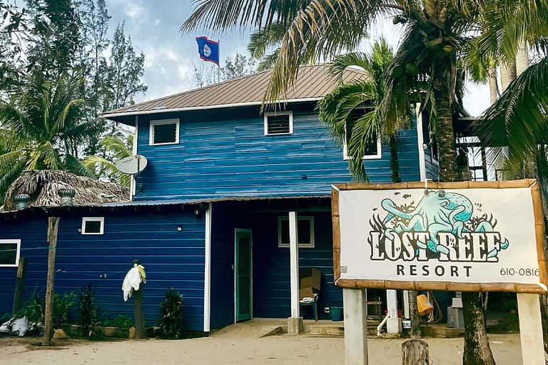 Blue wooden beach house with palm trees and Lost Reef Resort sign