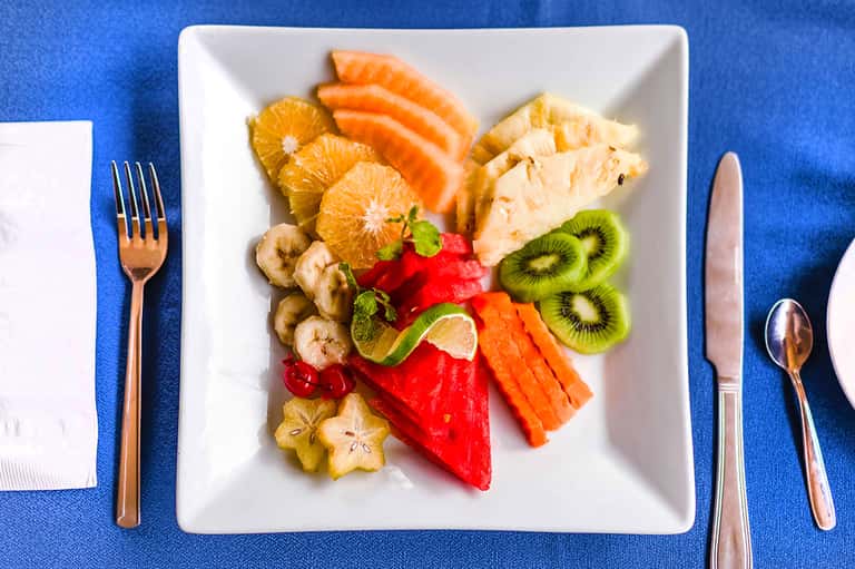 Elegant fruit and protein plate with citrus, kiwi, and salmon on blue tablecloth