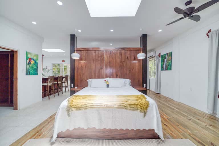 Spacious modern bedroom with wooden accent wall, king bed, and open floor plan with kitchen area