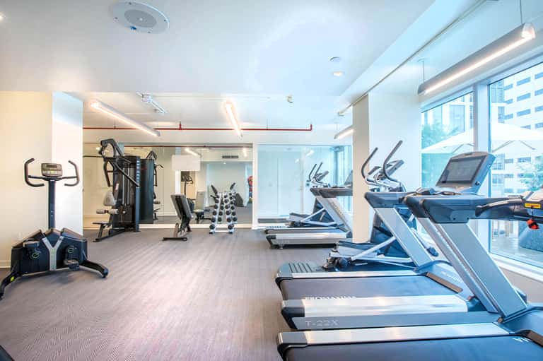 Bright modern fitness center with treadmills, exercise bikes, and city views