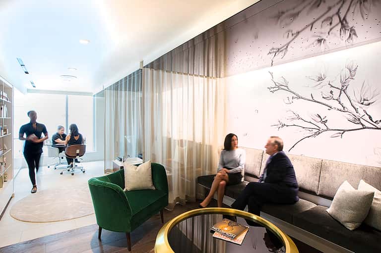 Modern office lounge with employees, featuring green armchair and contemporary wall art