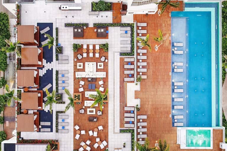 Aerial view of resort courtyard with pool, lounge chairs, and wooden deck area