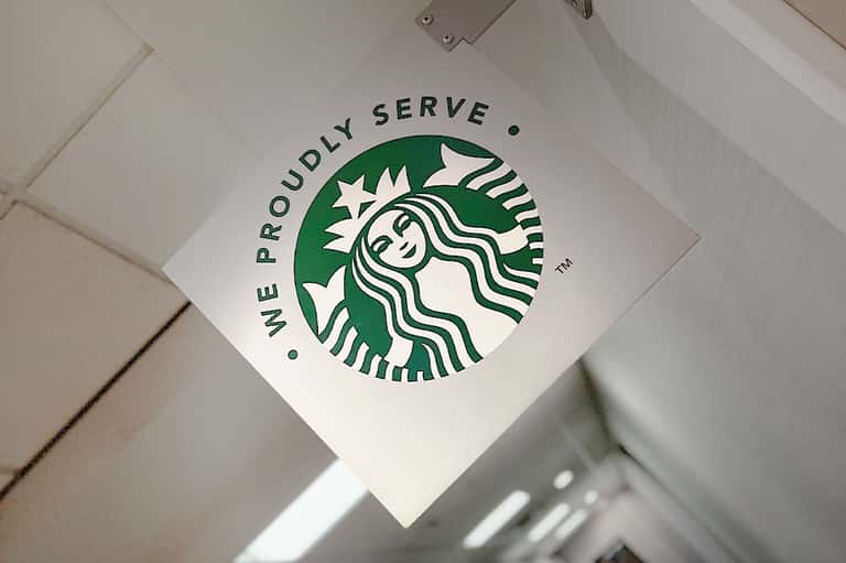 Starbucks logo with 'We Proudly Serve' text on ceiling