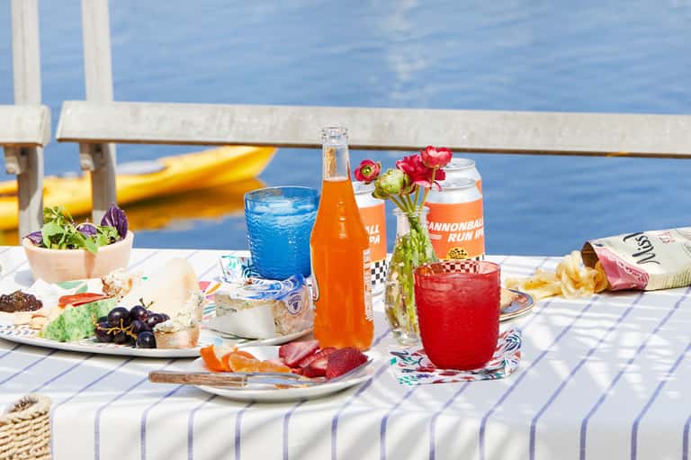 Beachside lunch table with beverages, snacks, flowers, and ocean view with yellow kayak