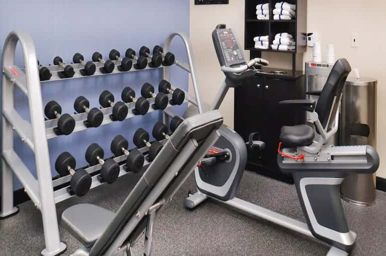 Modern fitness center with dumbbell rack, exercise bikes, and gym equipment in well-lit room