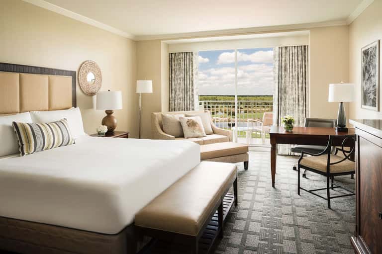 Elegant hotel bedroom with ocean view balcony, neutral tones, and contemporary furnishings