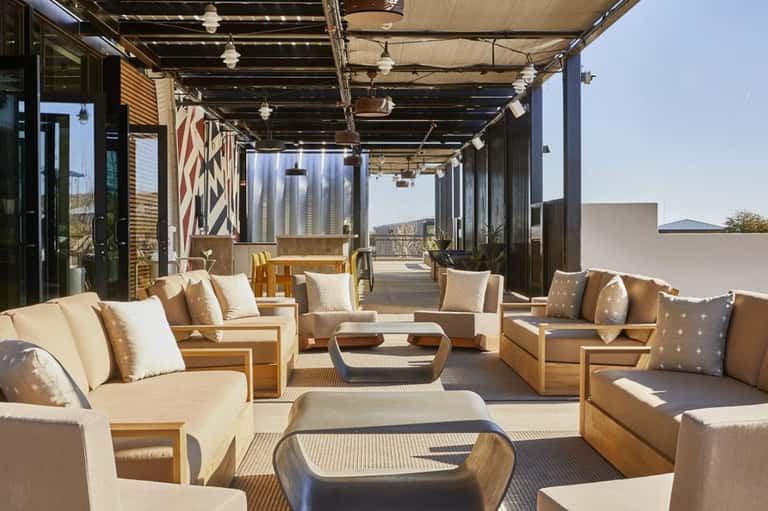 Contemporary covered terrace with tan seating, wooden furniture, and mountain views