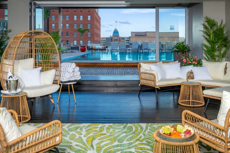 Luxury spa lounge with woven chairs, white cushions, and floor-to-ceiling windows overlooking rooftop pool