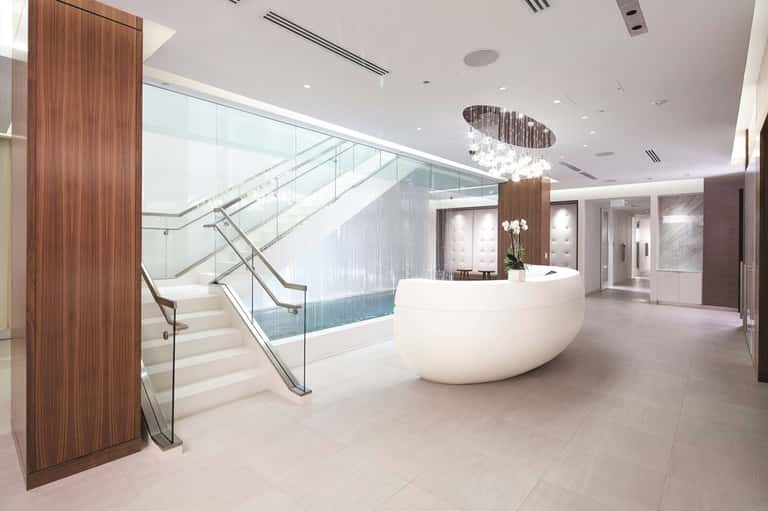 Modern hotel lobby with curved reception desk, grand staircase, and contemporary lighting