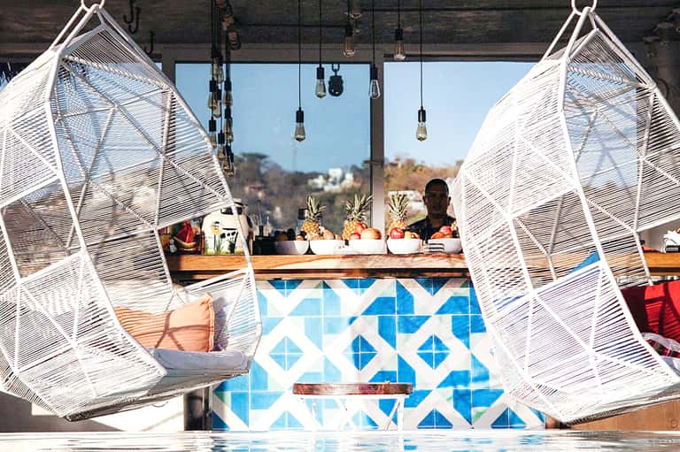 Resort bar area with white woven hanging chairs and geometric blue tile design