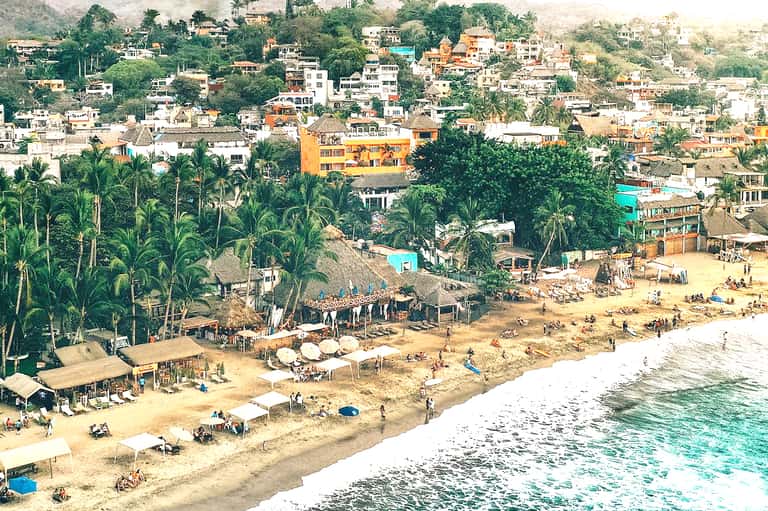Colorful hillside beach town with mixed residential and commercial buildings along sandy shore