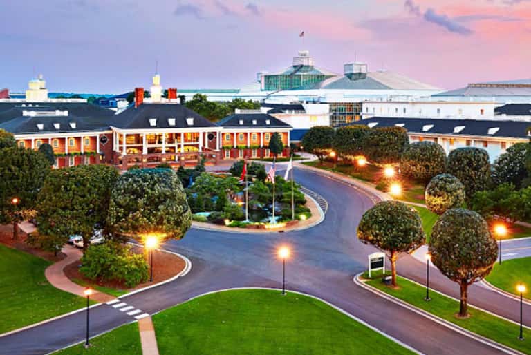 Elegant hotel entrance at dusk with manicured grounds, curved driveway, and illuminated landscaping