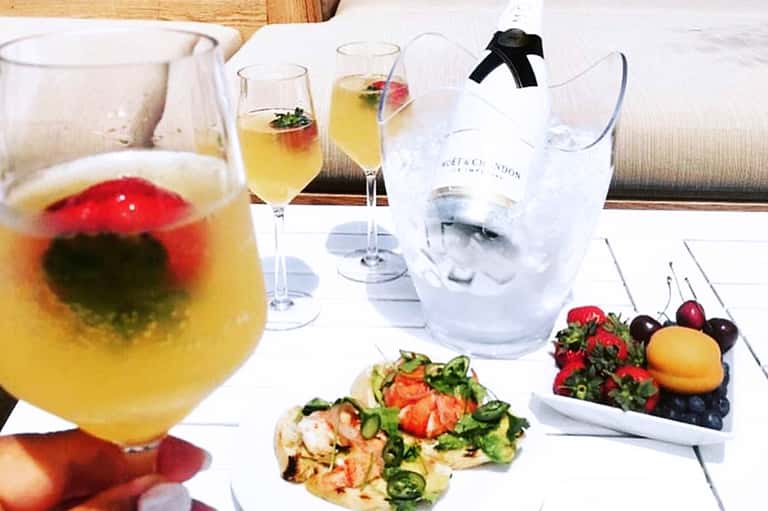 Fine dining table setting with tropical cocktails, fresh fruit, appetizers, and champagne