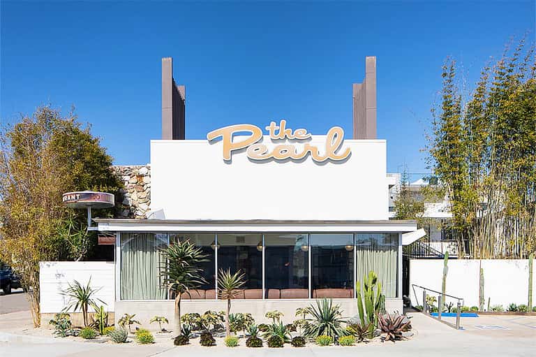 Vintage white retro diner storefront with 'The Pearl' signage and desert landscaping