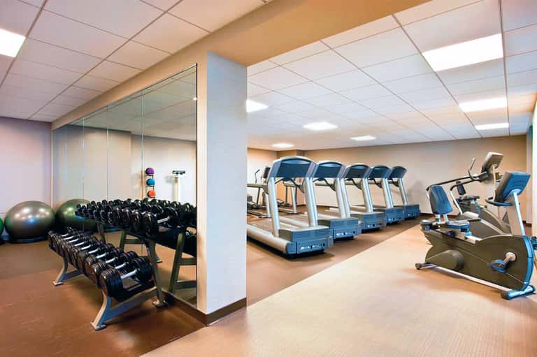 Hotel fitness center with treadmills, dumbbells, exercise balls, and mirrored walls
