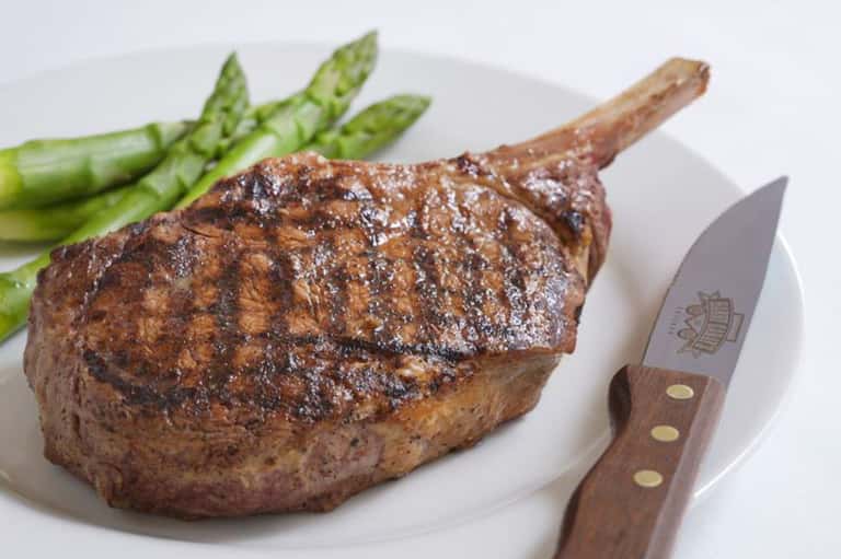 Grilled steak with asparagus on white plate with steak knife