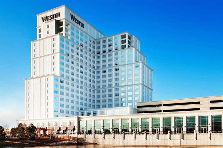 Westin hotel tower with glass facade and ground-level glass entrance by waterfront
