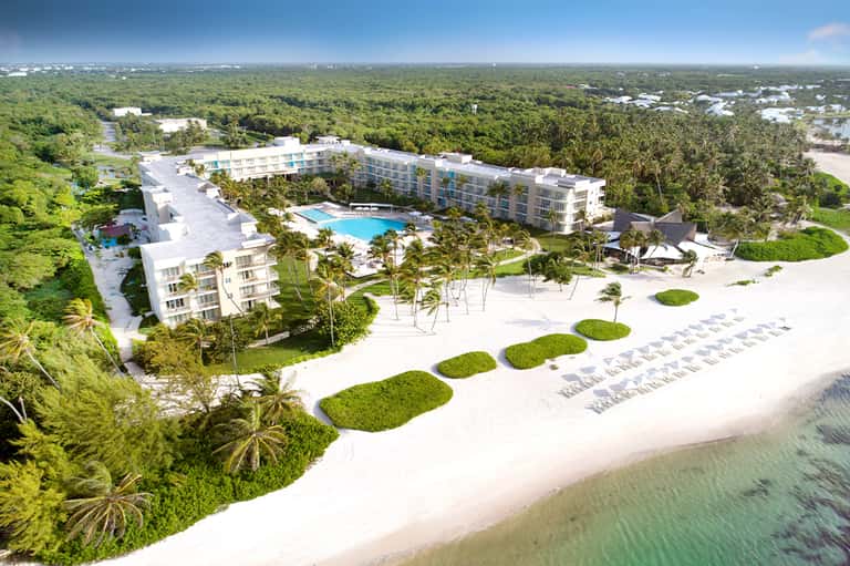 Aerial view of beachfront resort with curved pools, white sand, and tropical landscaping
