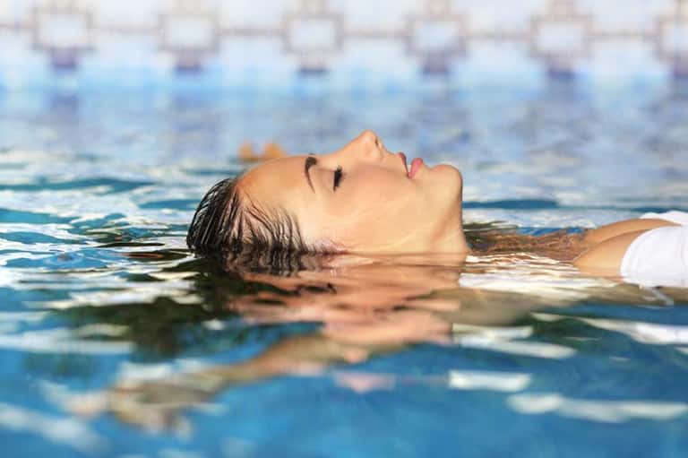 Woman floating peacefully in clear blue pool water