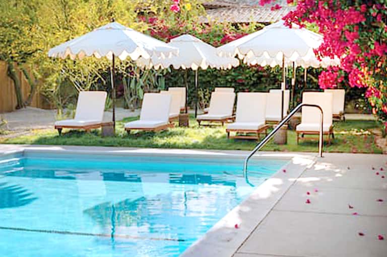 Luxury poolside with white umbrellas, lounge chairs, and blooming magenta flowers
