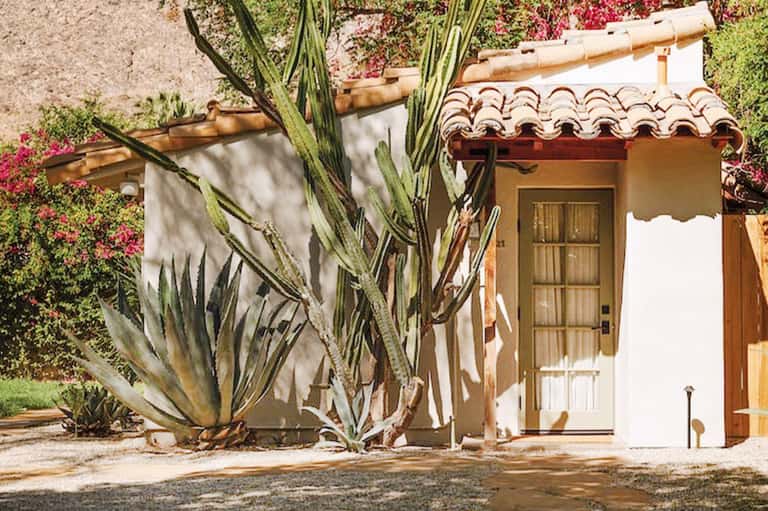 White Spanish colonial-style cottage with arched roof tiles, cactus plants, and magenta bougainvillea flowers