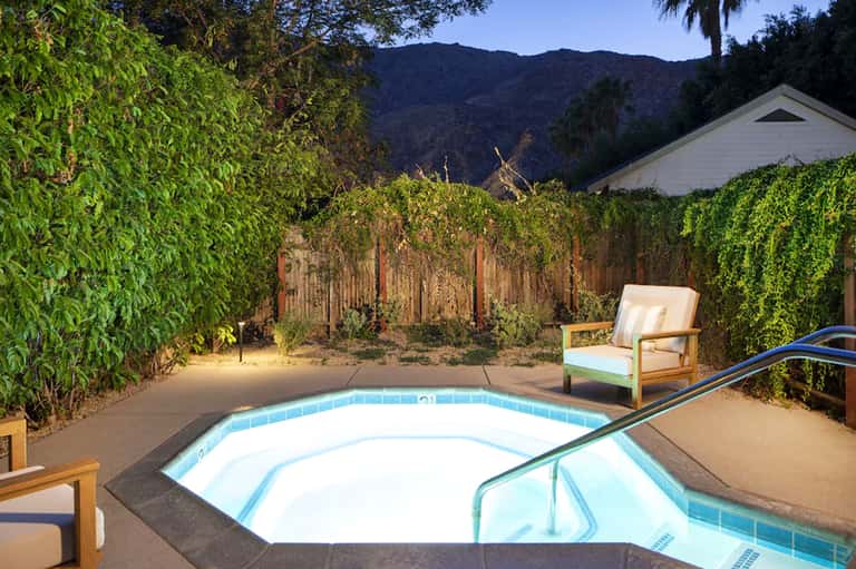 Hot tub surrounded by hedges with mountain views and lounge chairs