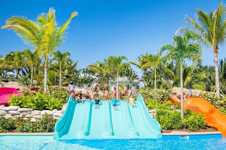 Colorful water slide complex with turquoise slides and palm trees at family resort pool