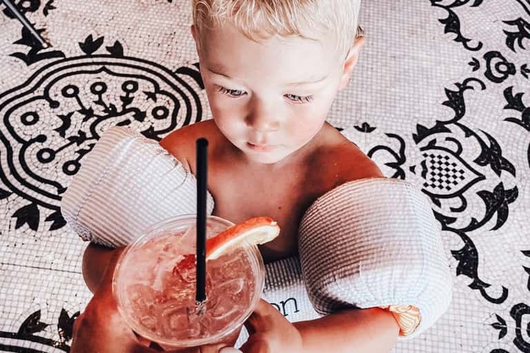 Toddler holding colorful beverage on patterned black and white background