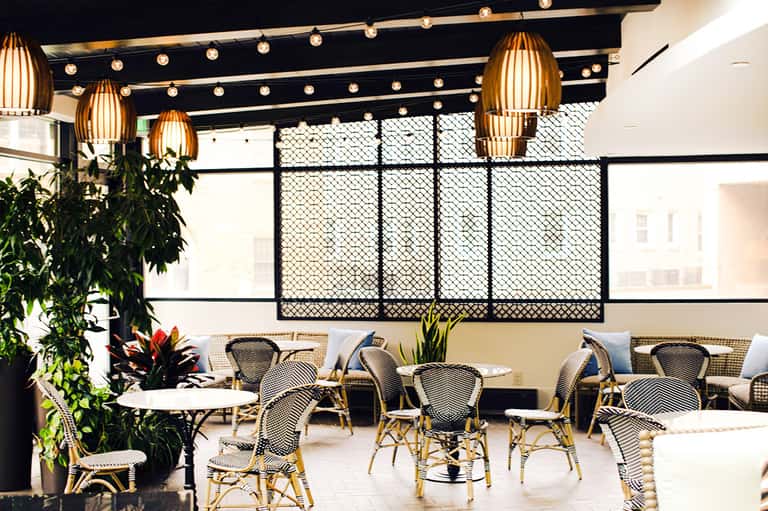 Contemporary restaurant interior with gold pendant lights, geometric screens, and dining tables
