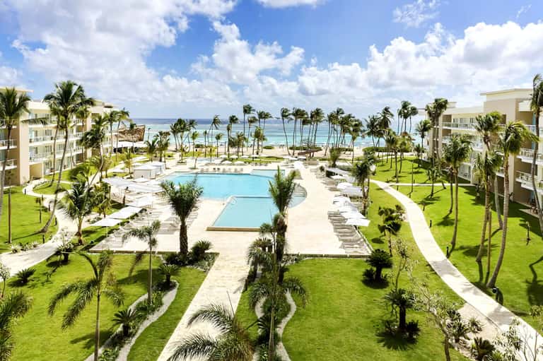 Beachfront resort with pool, palm trees, and ocean view with residential buildings