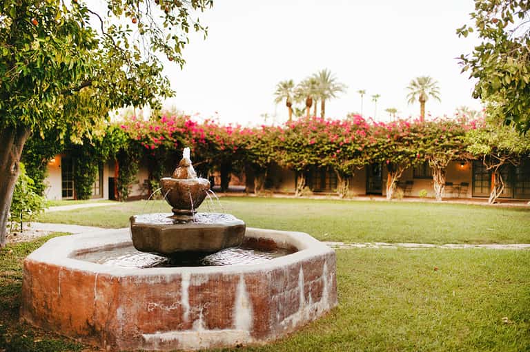 Tranquil courtyard with fountain, manicured lawn, and flowering vines