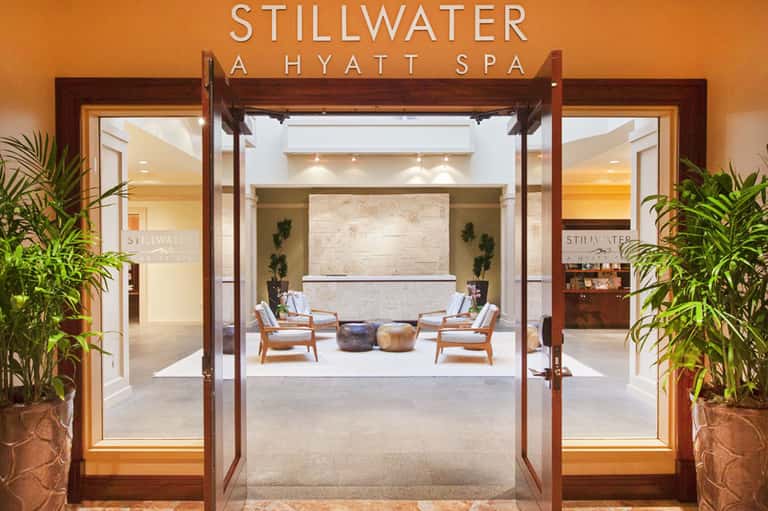 Stillwater spa entrance with wooden doors, lounge seating, and natural stone reception area