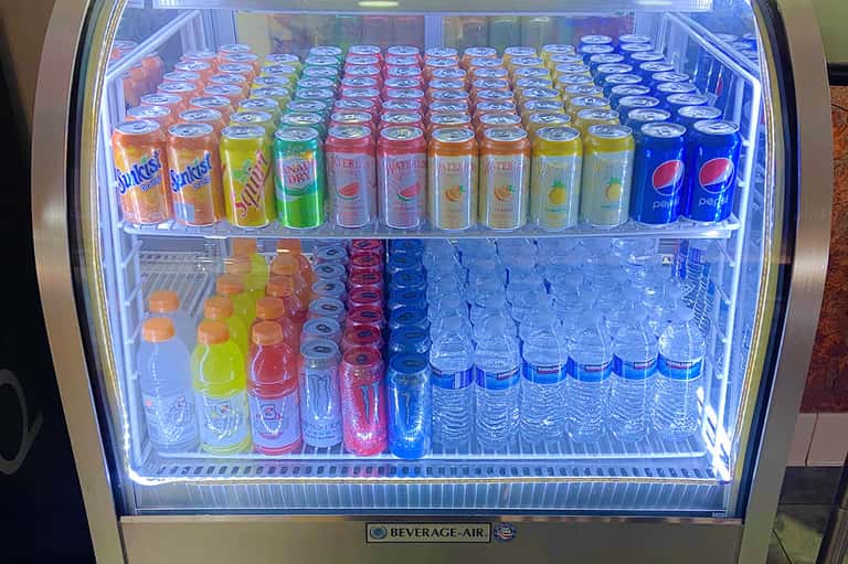 Refrigerated beverage cooler stocked with colorful soft drinks and bottled water