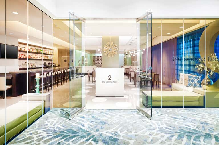 Modern hotel lobby entrance with glass doors, elegant bar area, and contemporary furnishings