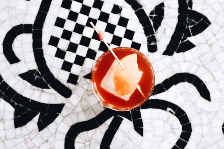 Cocktail with grapefruit slice on black and white geometric patterned tile poolside