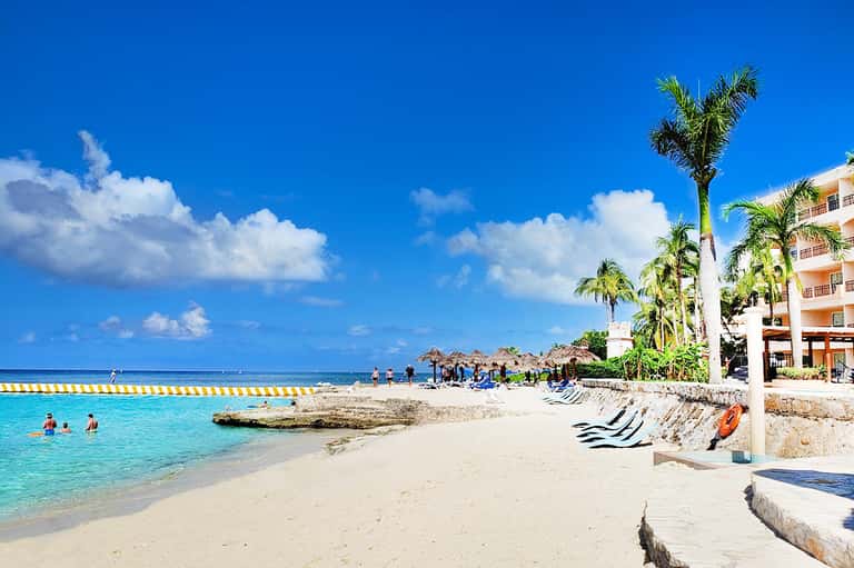 Caribbean beach resort with turquoise water, white sand, palm trees, and beachfront hotel
