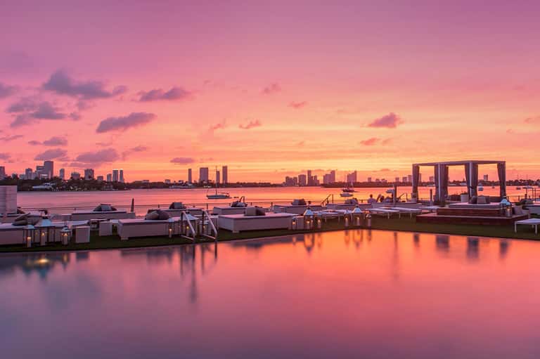 Sunset over waterfront with pink sky reflecting on calm water and modern marina docks