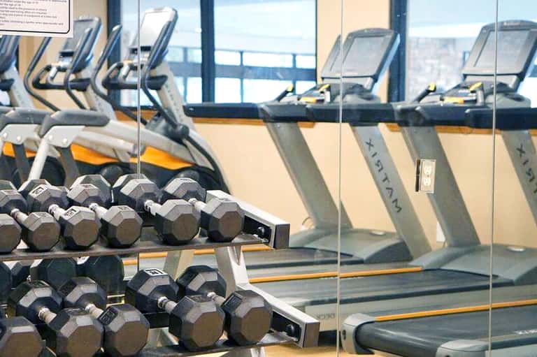 Fitness center with dumbbells in foreground, cardio equipment, and ocean view through windows
