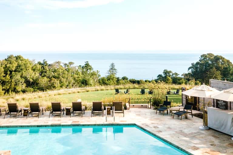 Resort pool with ocean view, lounge chairs, umbrellas, and coastal landscape