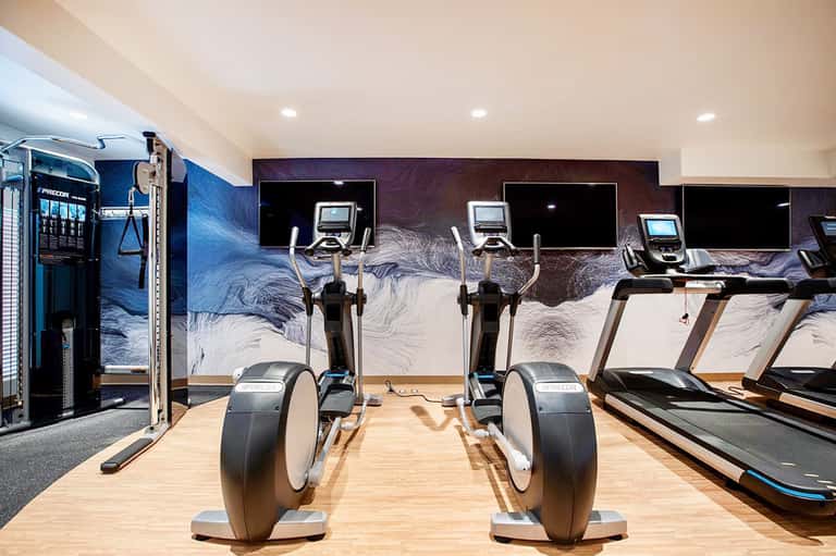 State-of-the-art gym with exercise bikes, artistic wall mural, and cardio equipment