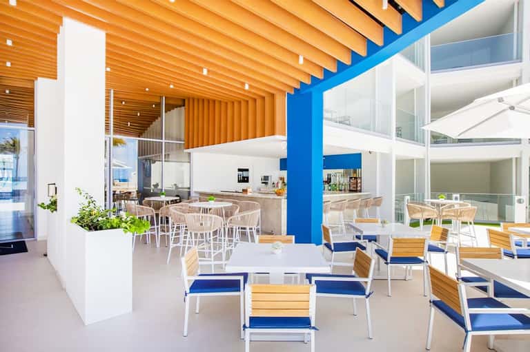 Modern resort dining area with wooden beams, blue accents, and ocean views