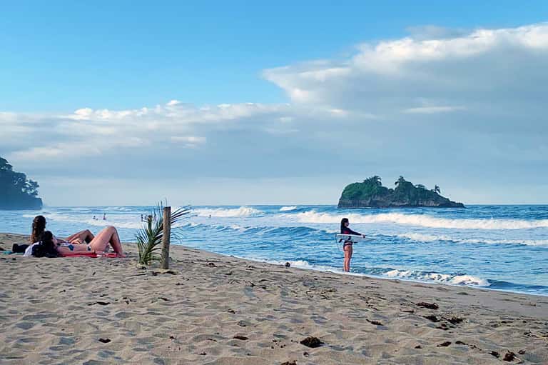 Surfer wading in ocean waves with island in background and beachfront
