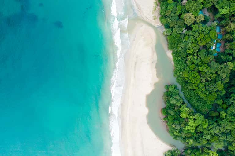 Aerial view of pristine turquoise beach, white sand, and lush tropical vegetation