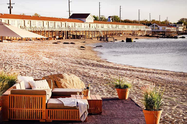 Beachfront lounge area with wooden cabanas and view of historic waterfront buildings