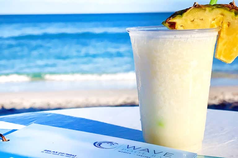 Tropical beach cocktail with pineapple garnish overlooking blue ocean and white sand