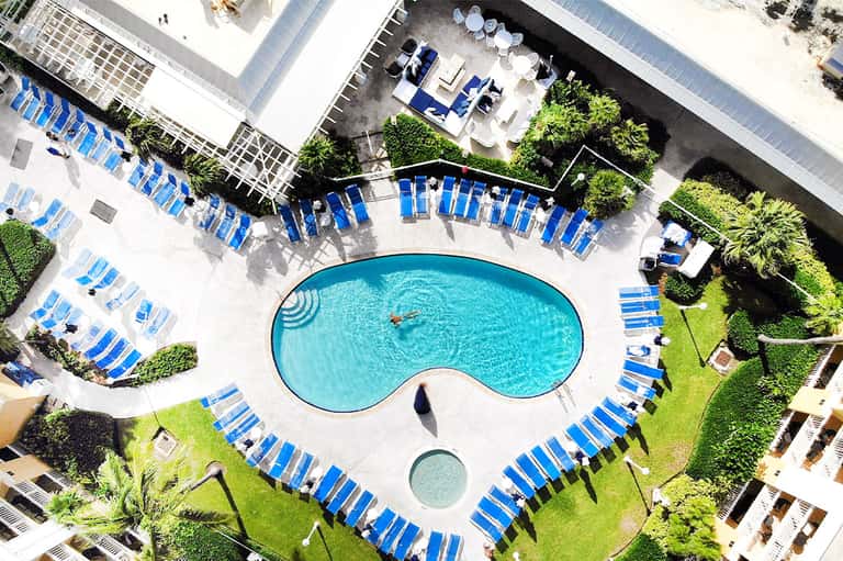 Aerial view of kidney-shaped pool surrounded by blue lounge chairs and manicured lawn