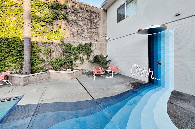 Modern resort entrance with blue wave-patterned pavement, living wall, and pink lounge chairs