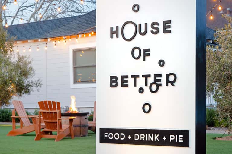 House of Better restaurant sign with firepit seating area and modern white building exterior
