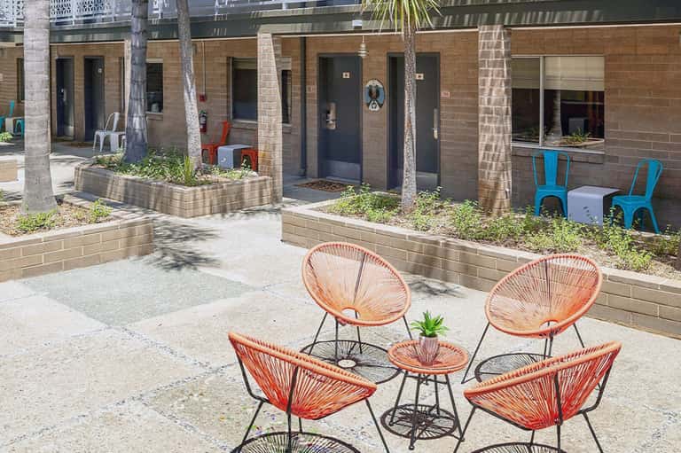 Courtyard seating area with colorful woven chairs and tropical plants in urban setting