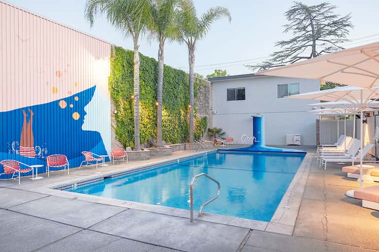 Contemporary resort pool with artistic blue sculpture, palm trees, and lounge seating